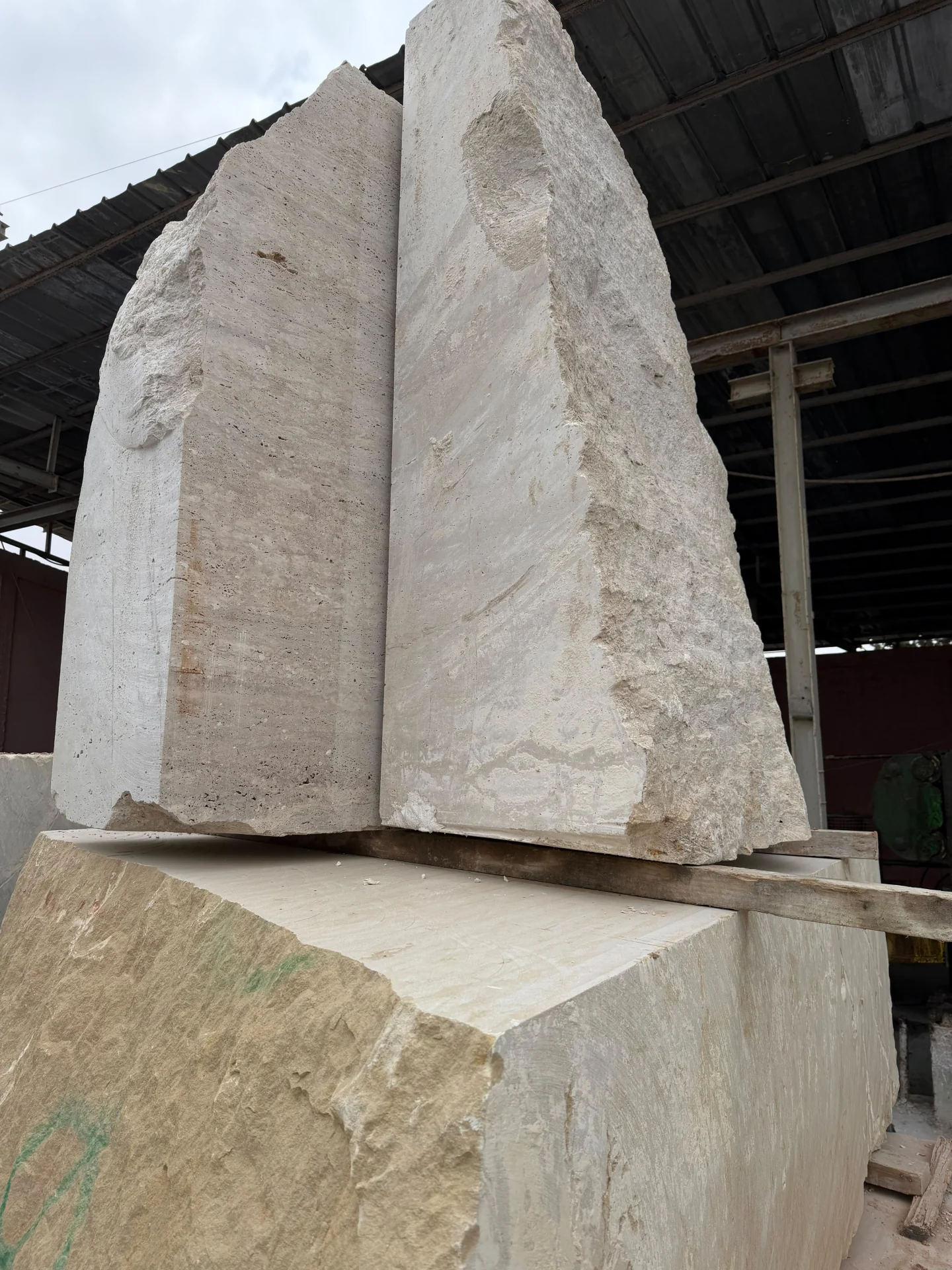 Tall beige natural stone blocks positioned in a processing yard