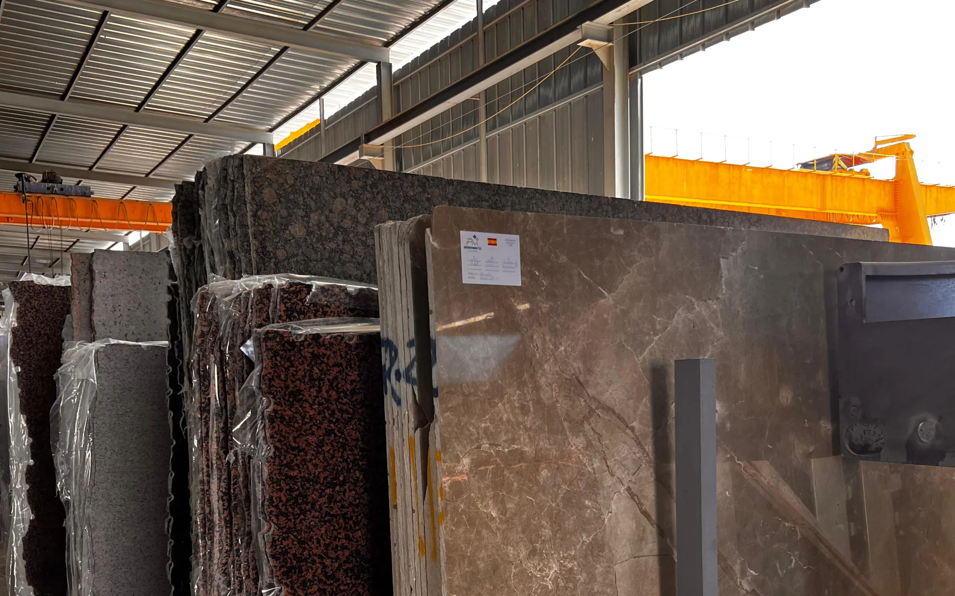 Natural stone and marble slabs stored upright inside the Tesmar production facility